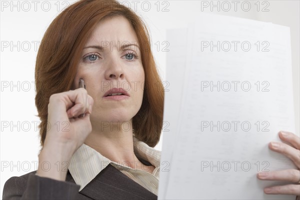 Businesswoman reading papers thoughtfully.