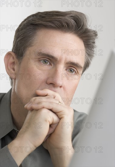 Businessman looking thoughtfully at computer monitor.