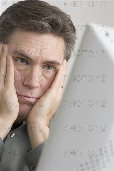 Discouraged man looking at computer monitor.