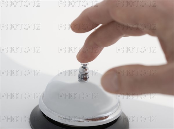 Closeup of hand ringing desk bell.