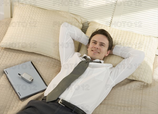 Closeup of businessman resting on bed.