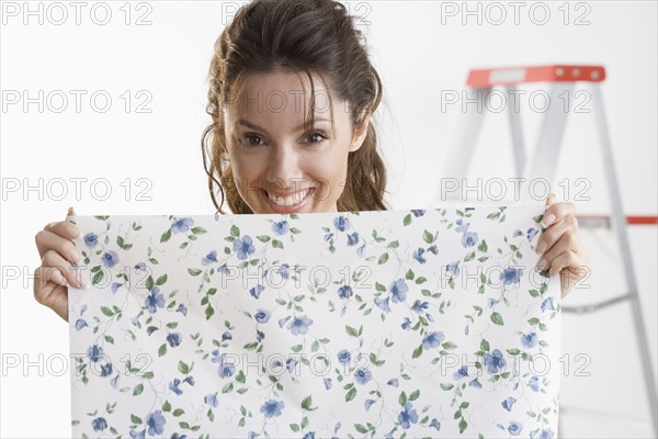 Smiling woman holding piece of wallpaper.