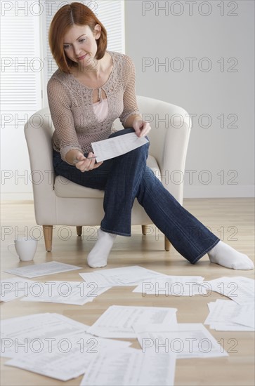 Redheaded woman sorting papers on floor.