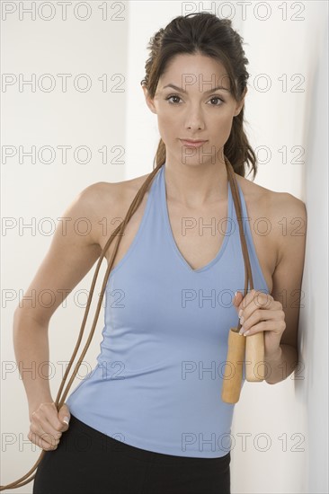 Woman with jump-rope leaning on wall.