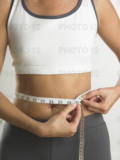 Closeup of woman measuring her waist.