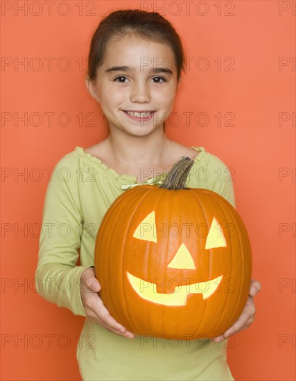 Smiling girl holding a jack o lantern.