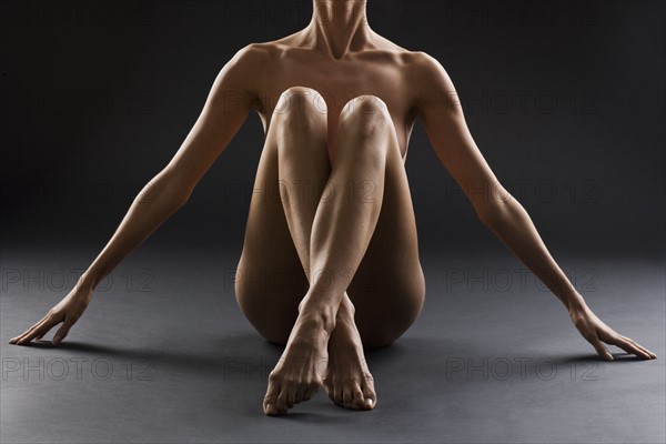 Nude female with legs crossed.