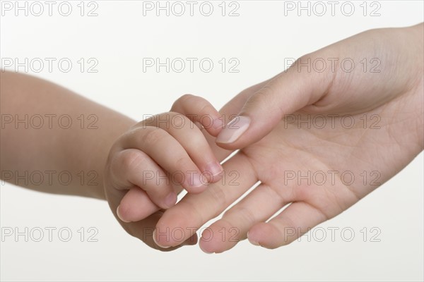 Baby holding hands with mother.