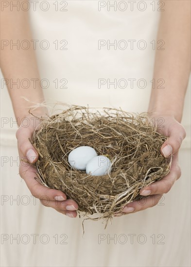 Female holding nest with eggs.