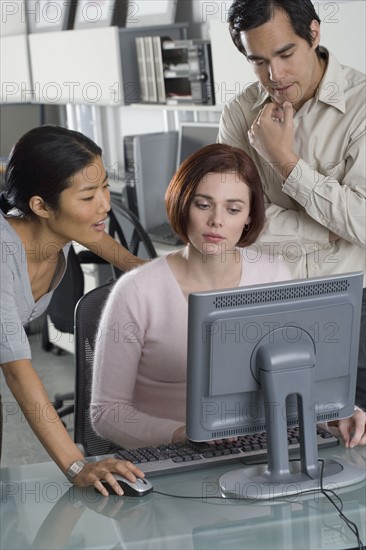 Office workers conferring at computer.