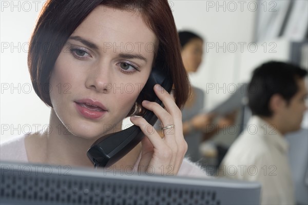 Woman talking on phone in office.
