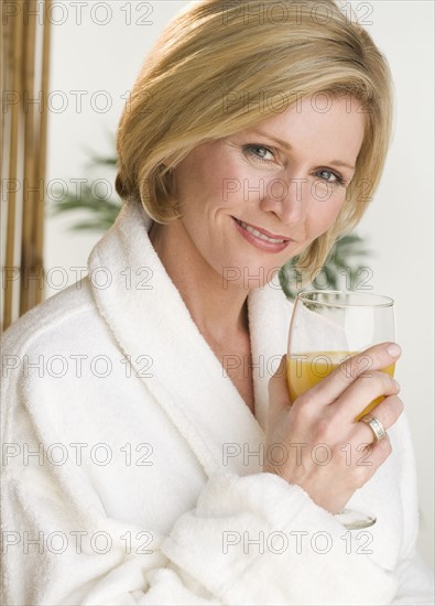 Woman holding glass of orange juice.