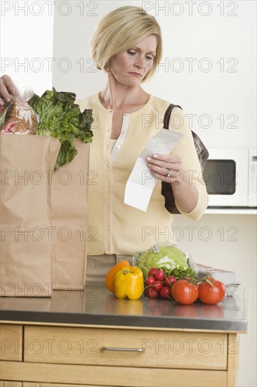 Woman checking grocery receipt.