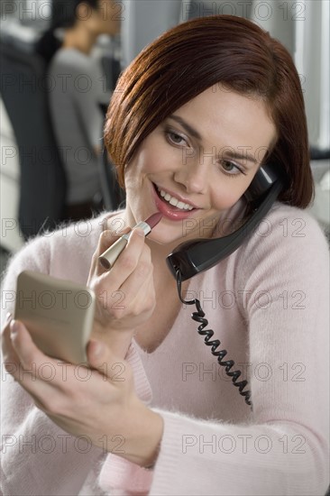 Woman at work applying lipstick.