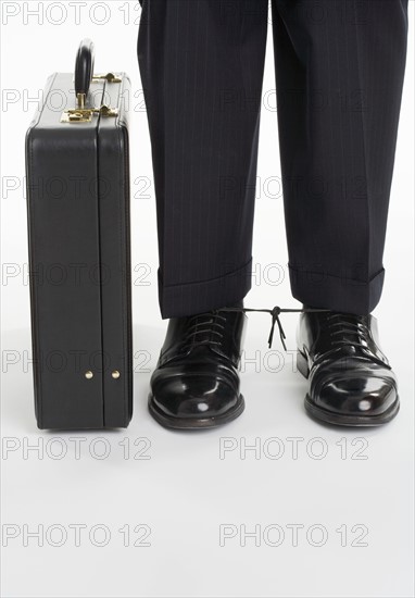 Businessman with shoelaces tied together.