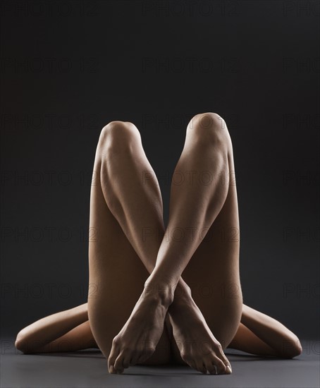 Nude female with legs crossed.