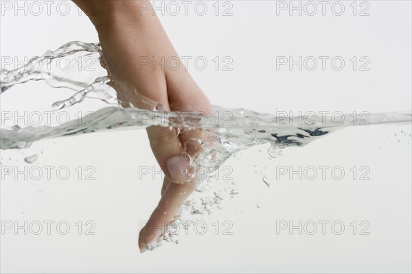 Hand dipping into water.