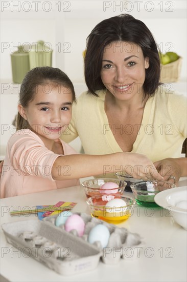 Mother and daughter coloring Easter eggs.