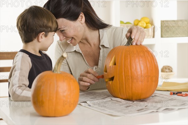 Mother and son carving pumpkin.