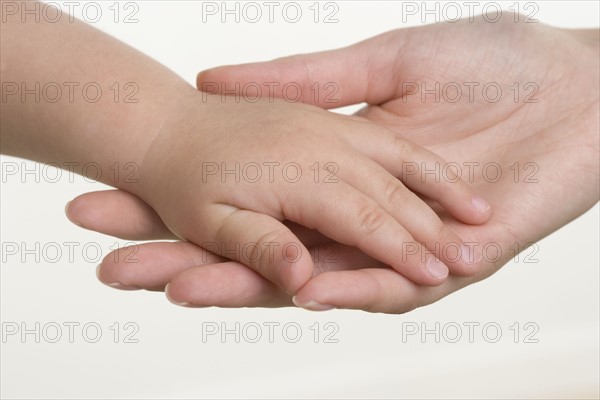 Baby holding hands with mother.