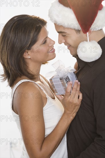 Man in Santa hat giving gift to woman.