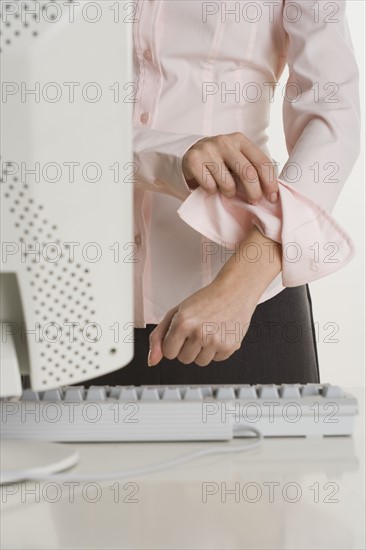 Woman rolling up sleeves at computer.