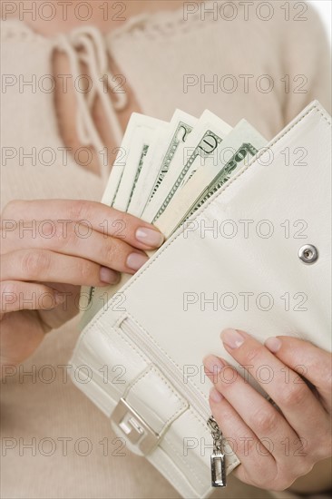 Woman putting cash in wallet.