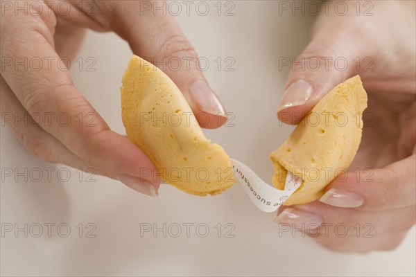 Woman breaking fortune cookie.