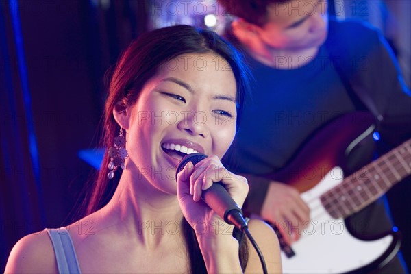 Woman singing into microphone with guitarist.
