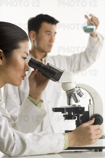 Scientists with beaker and microscope.