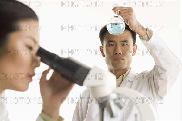 Scientists with beaker and microscope.