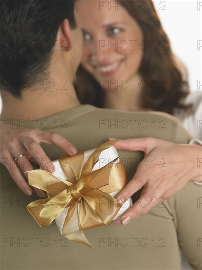 Woman holding gift with arms around man.