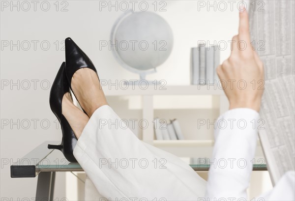 Woman reading newspaper business page.