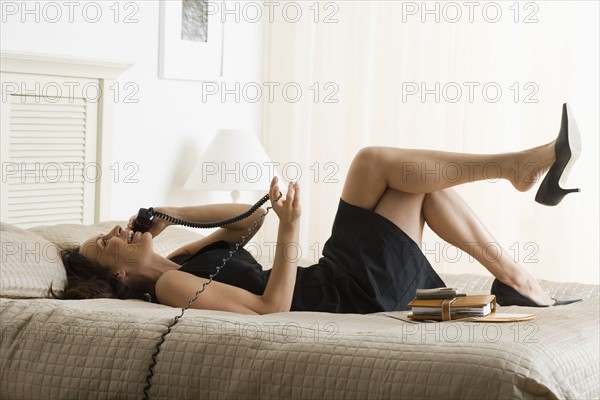 Woman lying on bed and talking on phone.