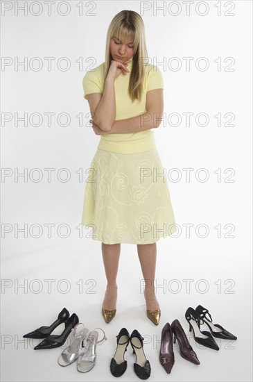 Studio shot of woman looking at many pairs of shoes.