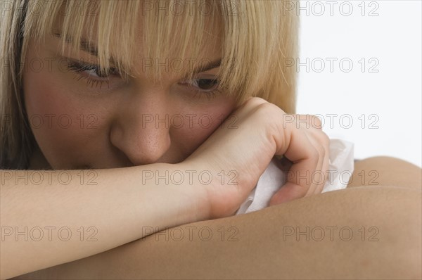 Sad woman with chin resting on her arms.