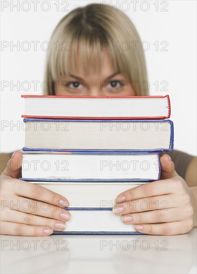 Studio shot of woman behind stack of books.