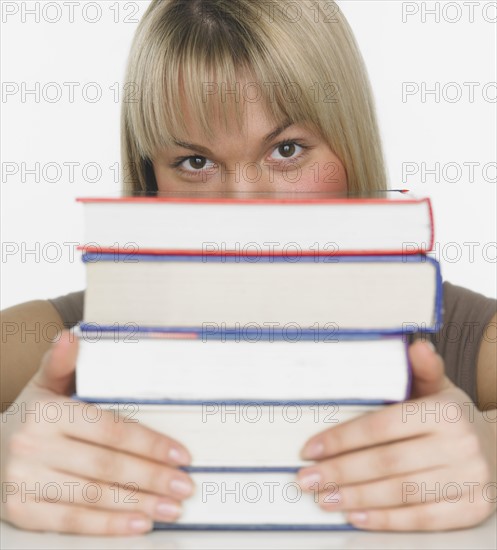 Studio shot of woman behind stack of books.