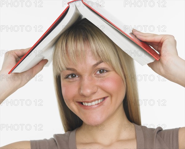 Studio shot of woman holding a book over her head.