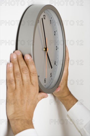 Close up of clock being put on wall.