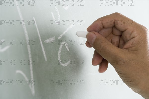 Close up of blackboard with math equations being written on it.