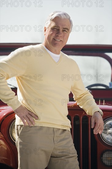 Senior man standing in front of jeep.