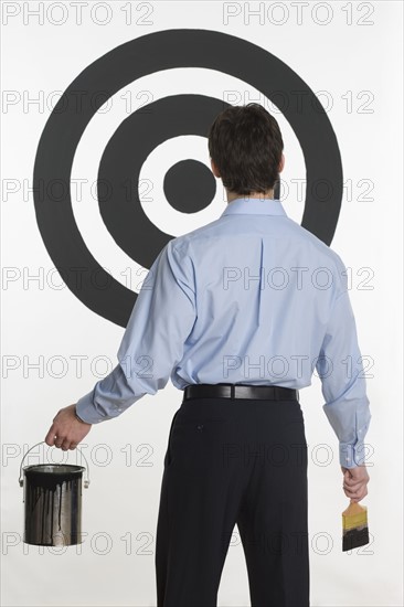 Man painting bull’s eye on wall.