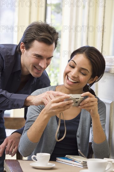 Couple looking at digital camera in restaurant.