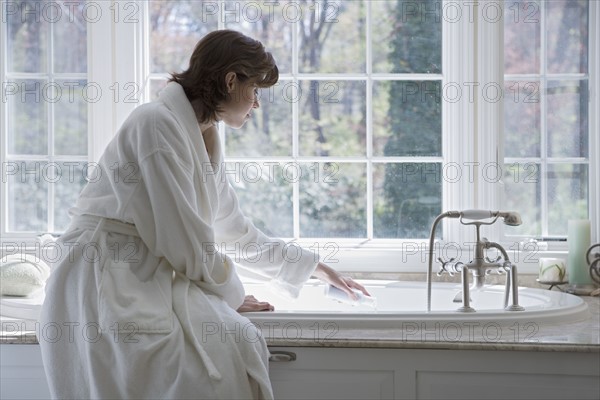 Woman in robe drawing bath.