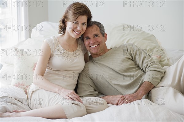 Couple sitting on bed.