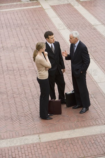 Three business people talking outdoors.