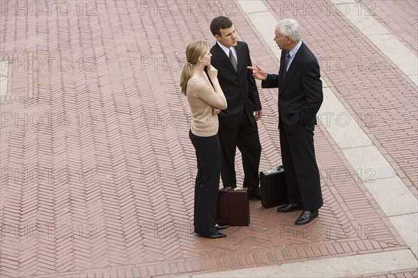 Three business people talking outdoors.