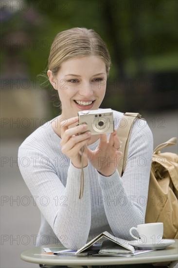 Woman with digital camera at outdoor café.
