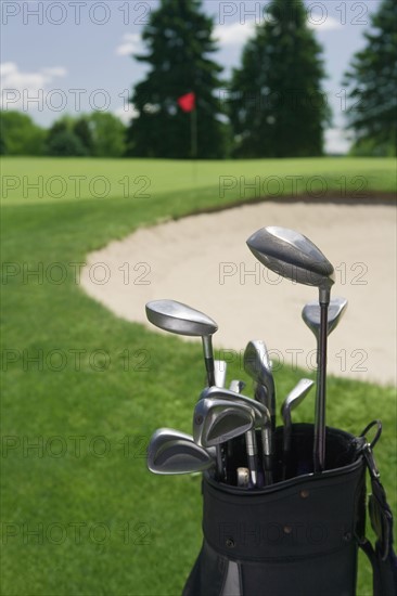 Golf clubs with course and sand trap in distance.